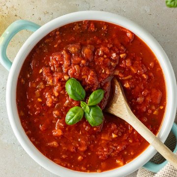 Vogelperspektive auf einen Topf mit einer italienischen Tomatensauce, mit Deko am Bildrand.