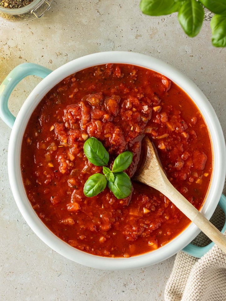 Vogelperspektive auf einen Topf mit einer italienischen Tomatensauce, mit Deko am Bildrand.