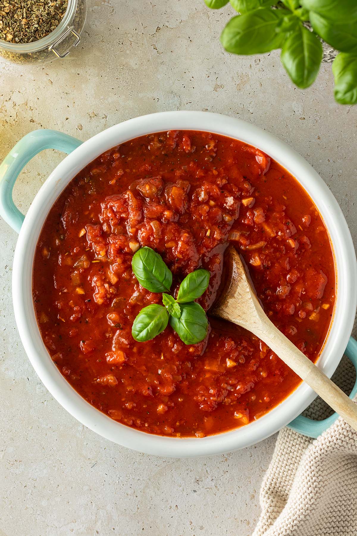 Vogelperspektive auf einen Topf mit einer italienischen Tomatensauce, mit Deko am Bildrand.