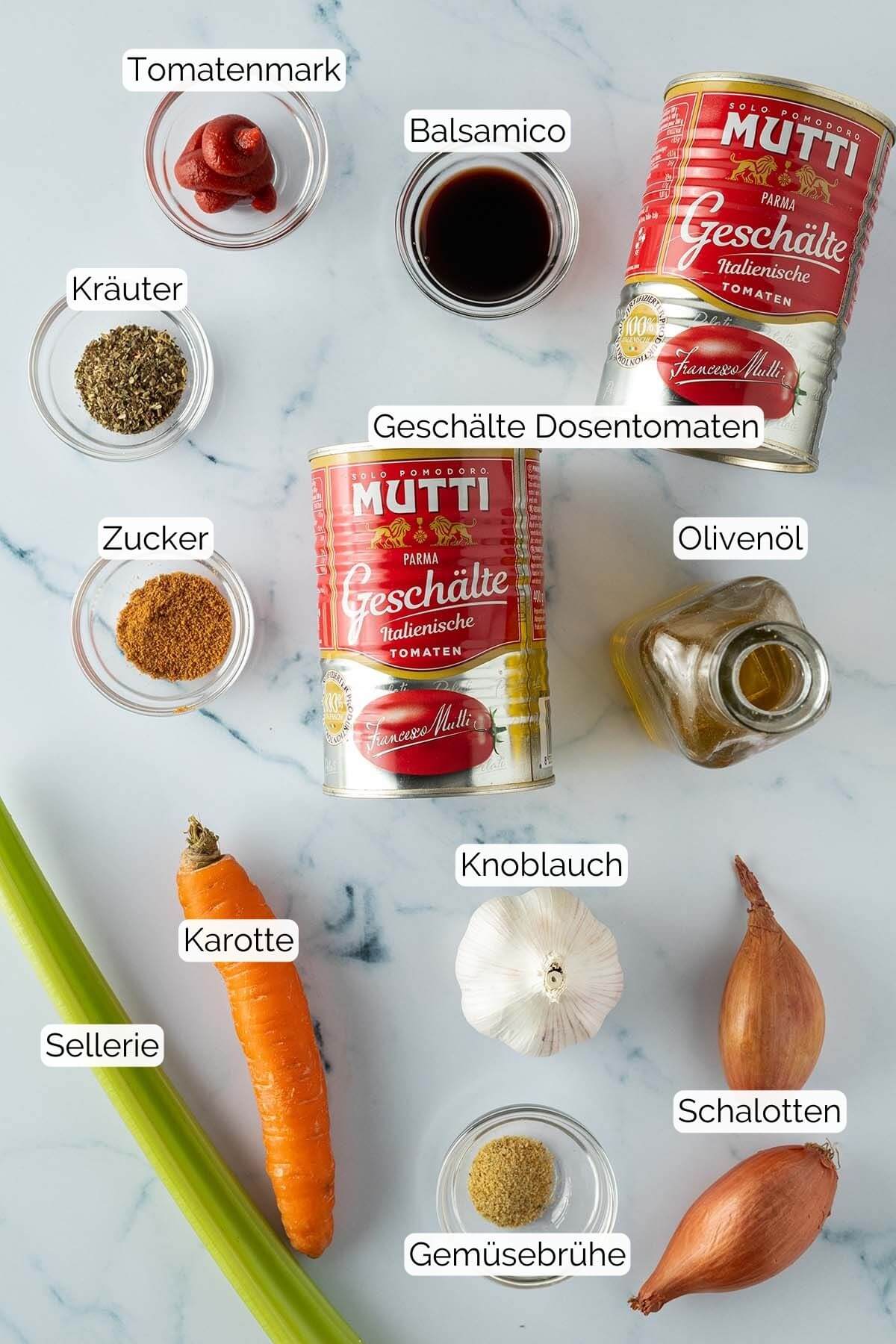 Bild aller Zutaten, die f&uuml;r die Tomatensauce ben&ouml;tigt werden, mit eingef&uuml;gten Beschriftungen zu jeder Zutat.