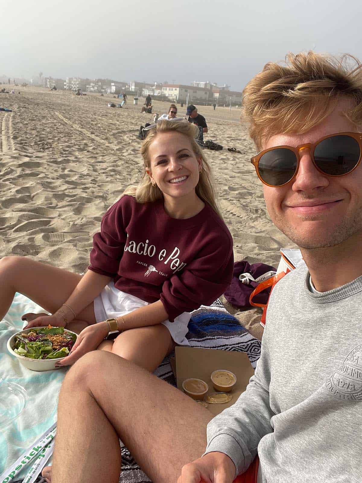 Paar sitzt am Strand beim Picknick.