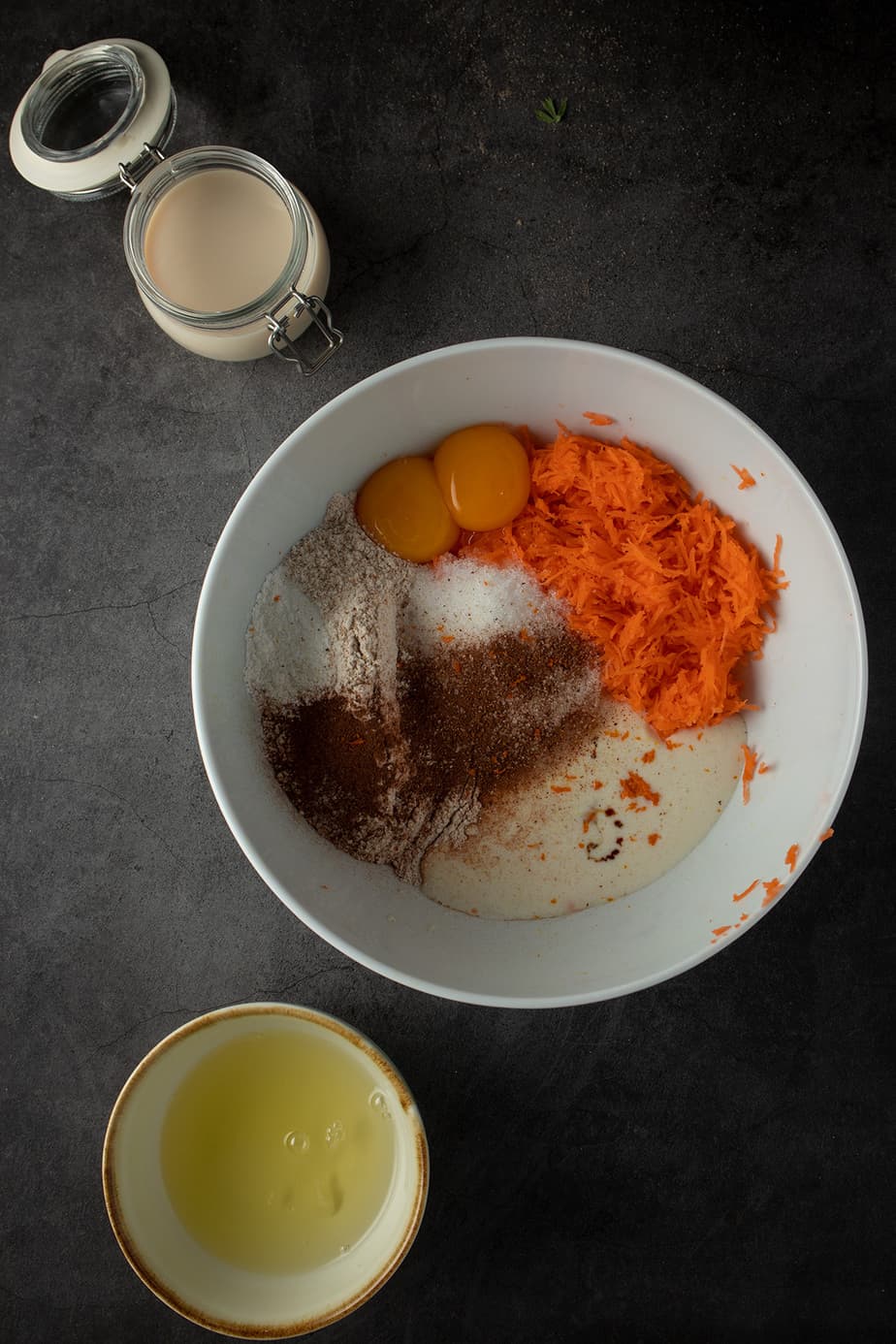 Zutaten in einer R&uuml;hrsch&uuml;ssel, daneben eine Sch&uuml;ssel mit Eiwei&szlig; und ein Glas mit Milch.