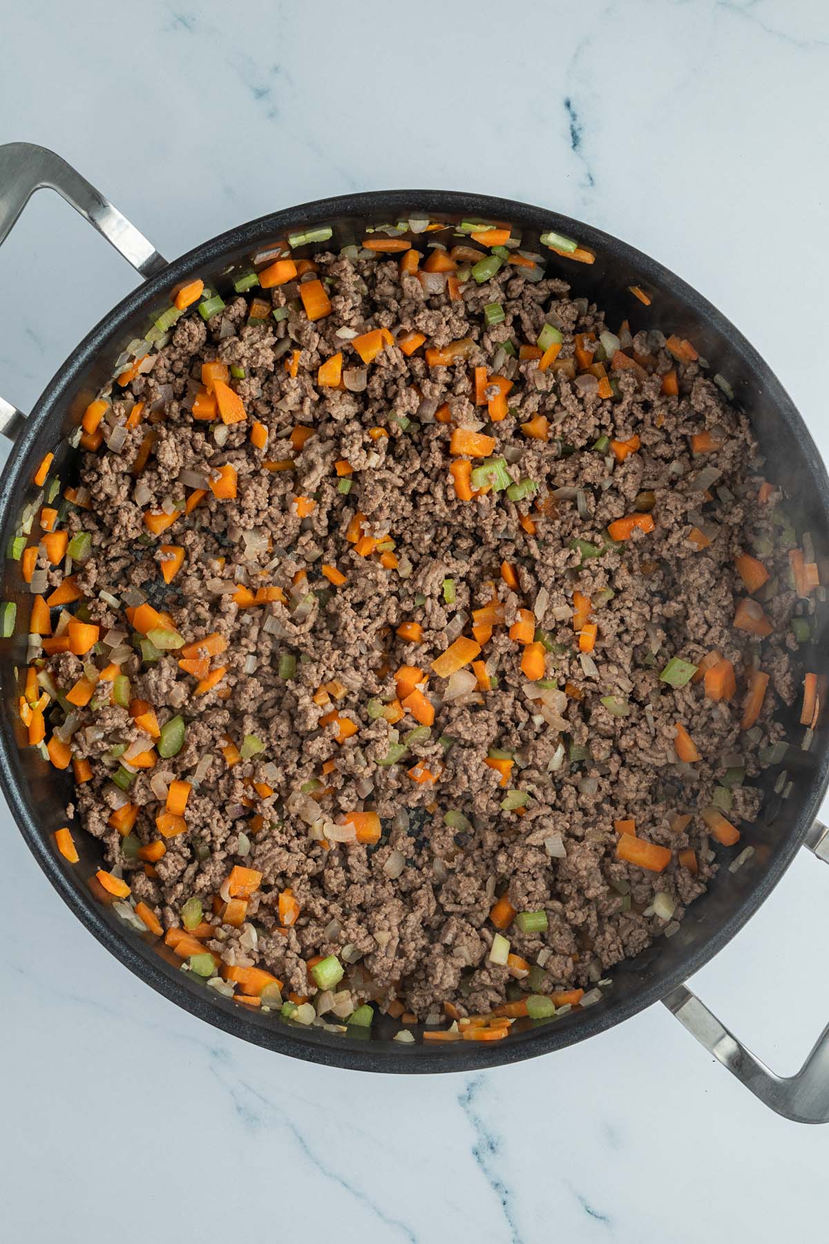 Eine Schmorpfanne, in der Hackfleisch und klein gew&uuml;rfeltes Gem&uuml;se angebraten wird.