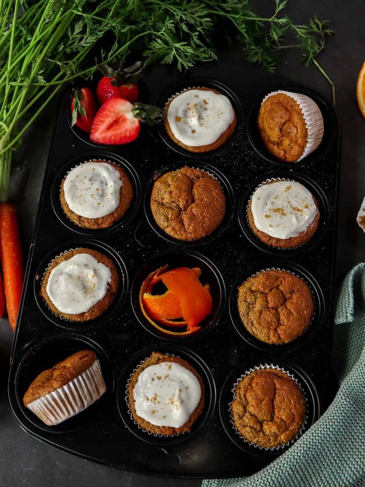 Kalorienarme Karottenmuffins in einem Muffig-Blech, ein Teil davon mit Frischkäse Frosting.
