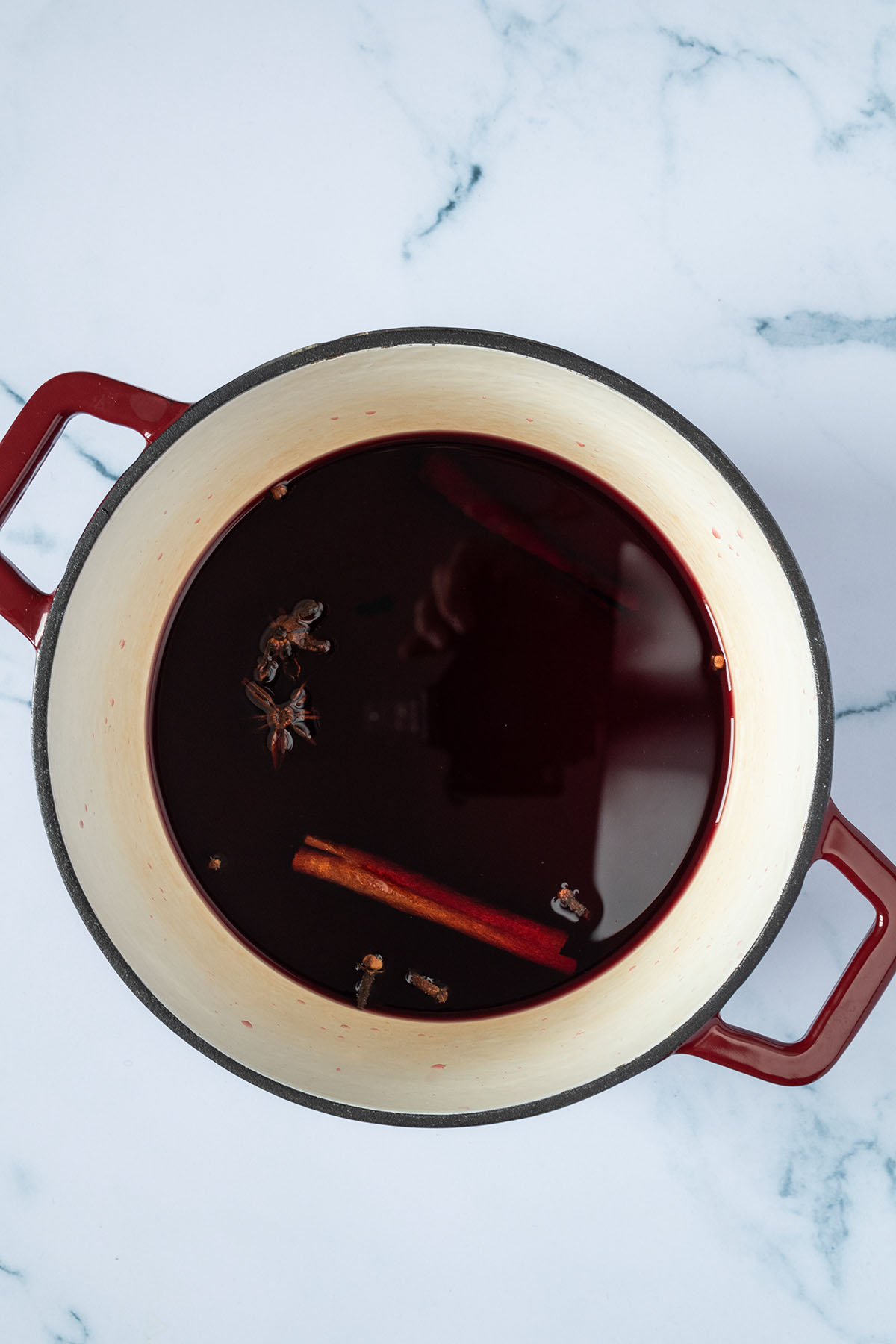 Rotwein und Gew&uuml;rze in einem massiven Gusseisentopf.