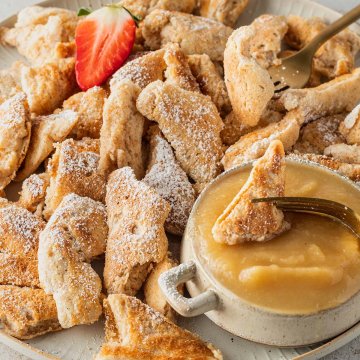 Ein Teller mit Kaiserschmarren, einer Sch&uuml;ssel Apfelmus und einer Erdbeere.