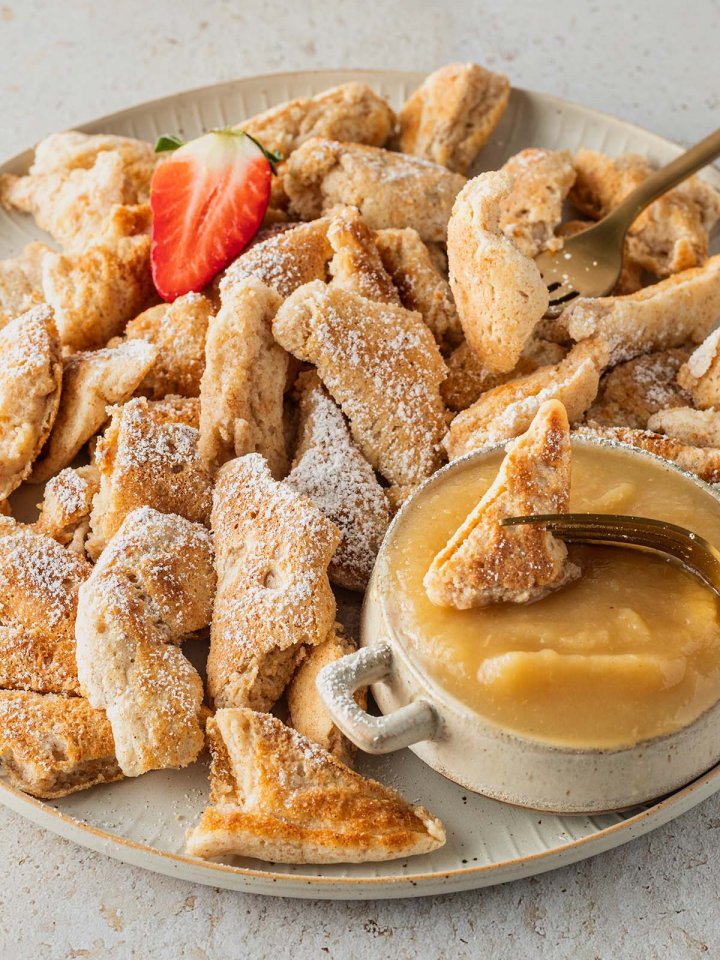 Ein Teller mit Kaiserschmarren, einer Sch&uuml;ssel Apfelmus und einer Erdbeere.