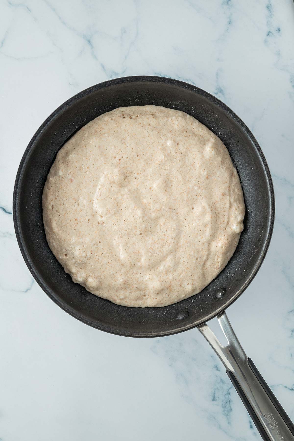 Ein dicker, gro&szlig;er Pfannkuchen in einer Pfanne.