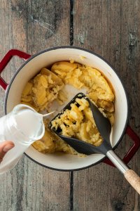 Kartoffeln werden zerstampft, währenddessen wird die Milch dazugegeben.