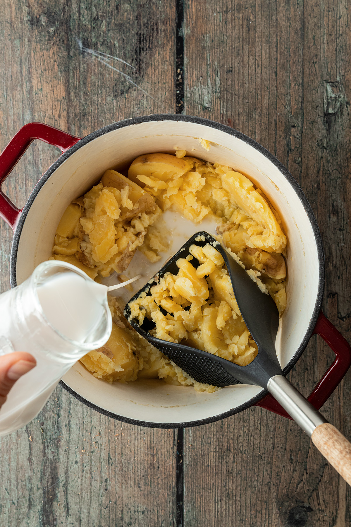Kartoffeln werden zerstampft, währenddessen wird die Milch dazugegeben.