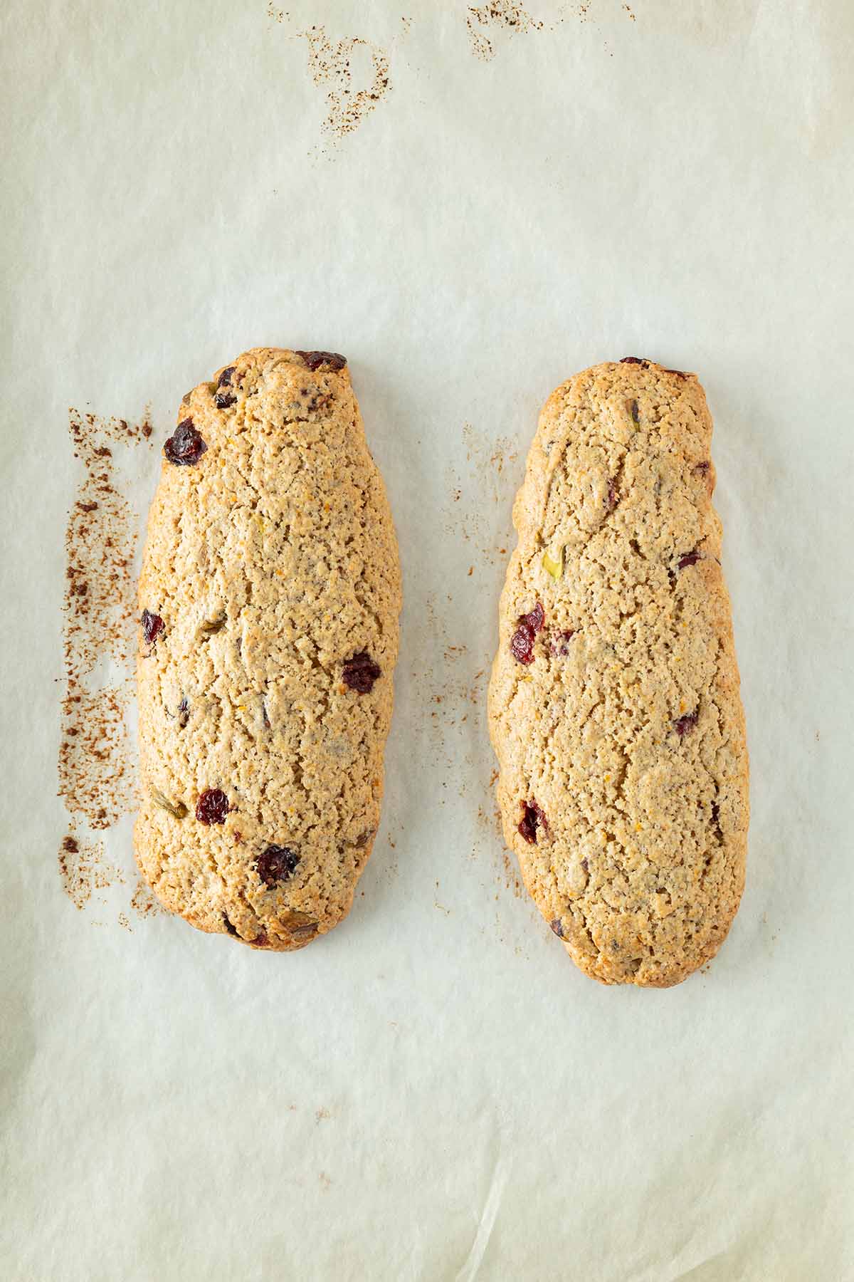 Zwei goldbraune Biscotti-Teigstr&auml;nge nach dem ersten Backen auf Backpapier.