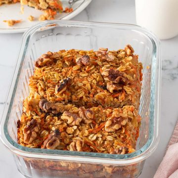 2 Portionen Karotten-Baked-Oats in einer Glasform, goldbraun gebacken mit Waln&uuml;ssen, eine Portion auf einem Teller mit einem Glas mit Milch im Hintergrund.