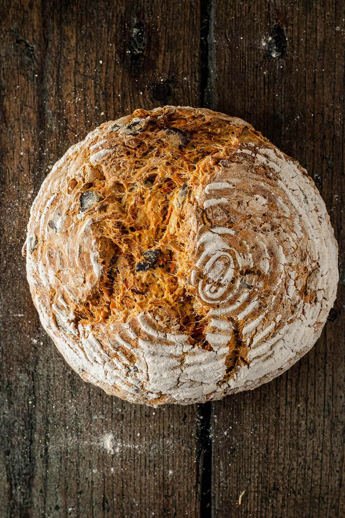 Vogelperspektive auf ein rustikales Karottenbrot auf einem Holzuntergrund.