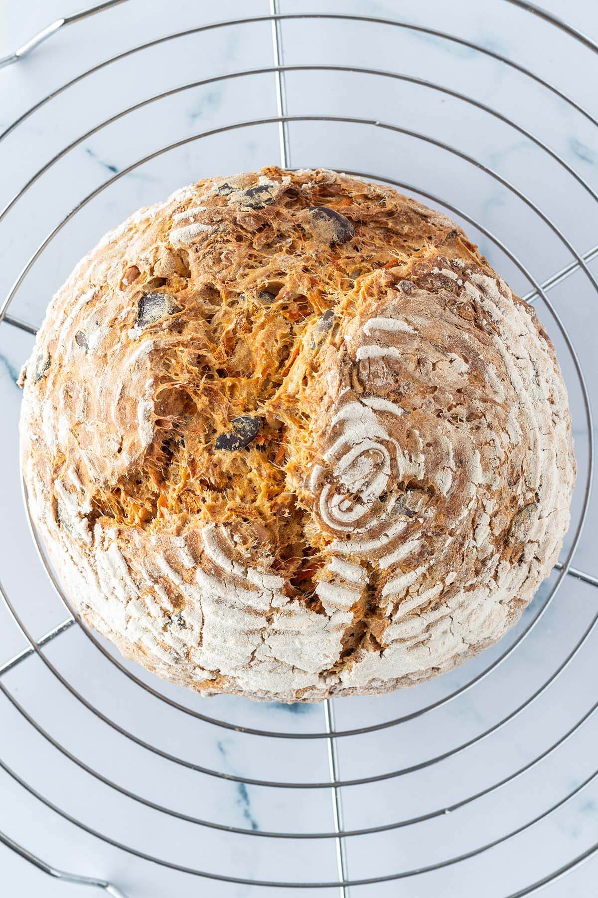 Vogelperspektive auf das fertig gebackene Karottenbrot, das auf einem Auskühlgitter ist.