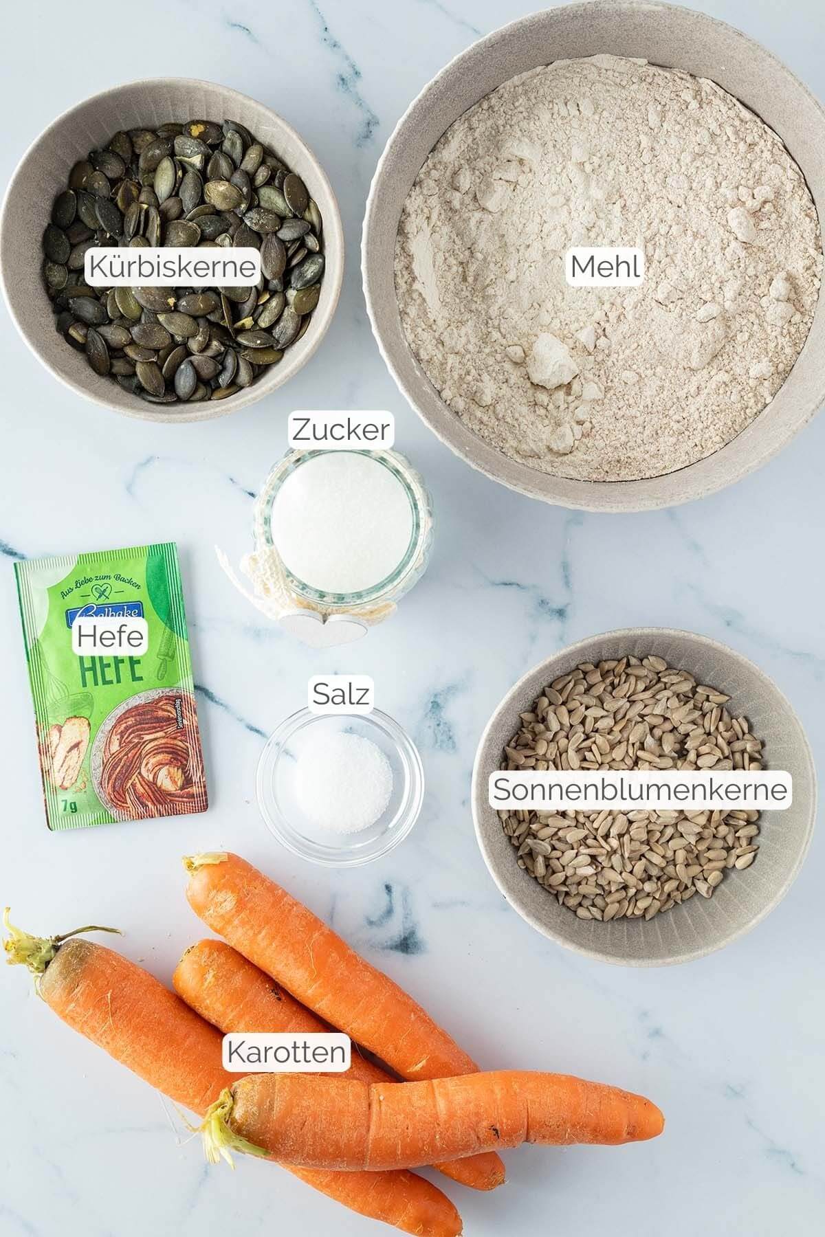 Foto aller Zutaten mit jeweiligen Textbeschriftungen, die das Karottenbrot benötigt werden.