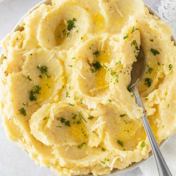 Ein luftiges Kartoffelp&uuml;ree in einer Sch&uuml;ssel mit Petersilie, etwas geschmolzener Butter und geriebenen K&auml;se als Garnitur.