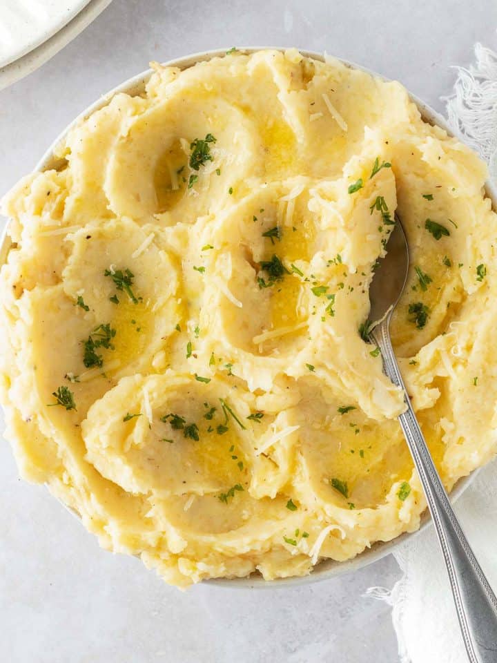 Ein luftiges Kartoffelp&uuml;ree in einer Sch&uuml;ssel mit Petersilie, etwas geschmolzener Butter und geriebenen K&auml;se als Garnitur.
