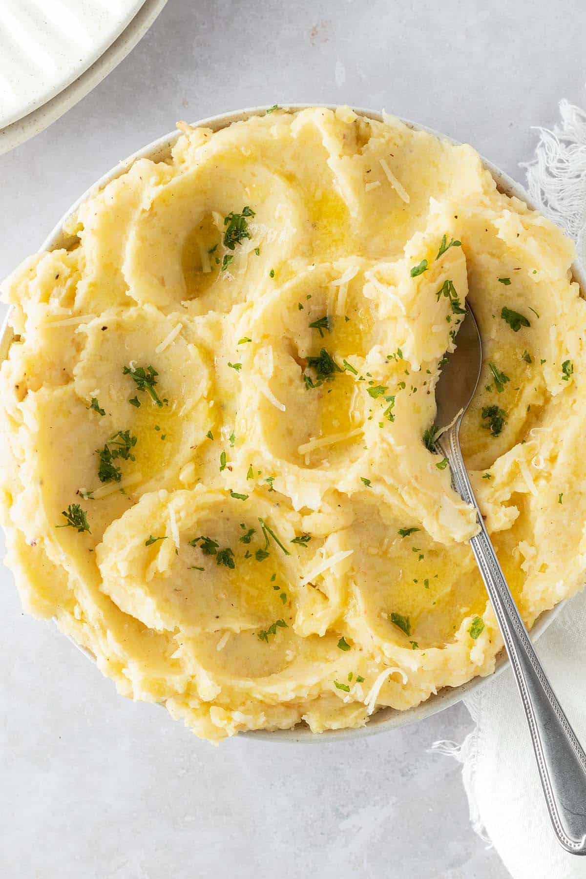 Ein luftiges Kartoffelp&uuml;ree in einer Sch&uuml;ssel mit Petersilie, etwas geschmolzener Butter und geriebenen K&auml;se als Garnitur.
