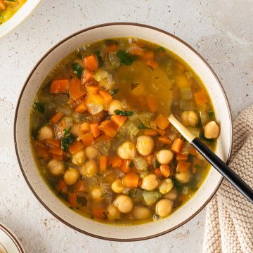 Sch&uuml;ssel mit Kichererbseneintopf aus Karotten, Sellerie und Br&uuml;he, Servierszene von oben fotografiert.