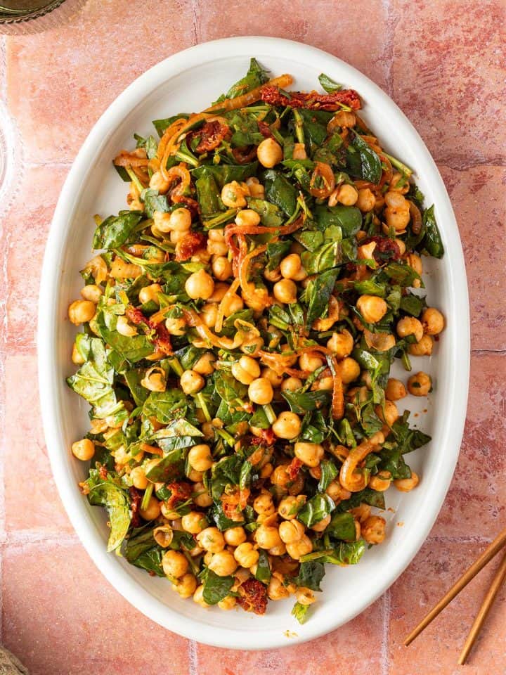 Orientalisch inspirierter Kichererbsensalat mit Spinat und Kr&auml;utern auf einem gro&szlig;en Servierteller.