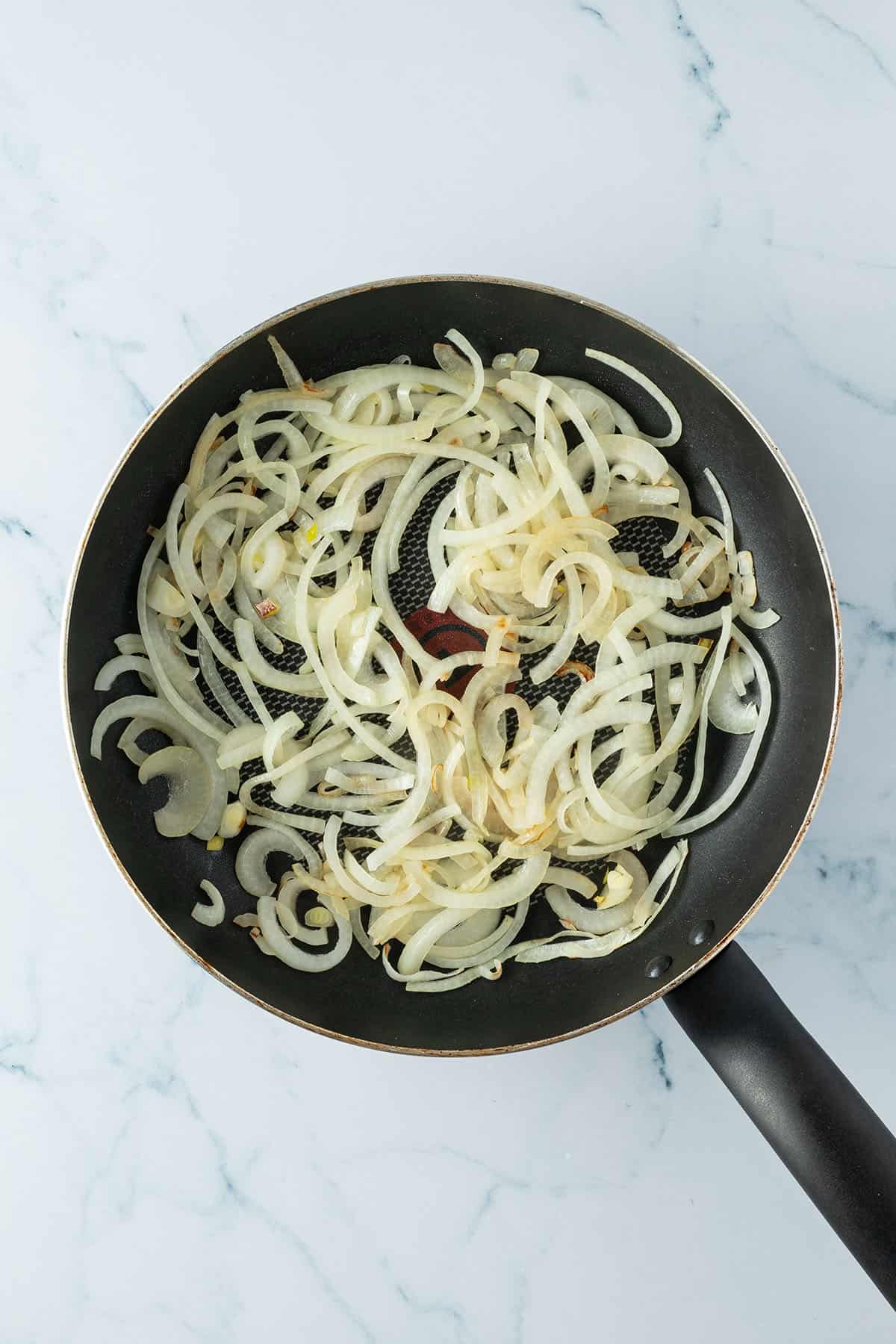 Glasig angebratene Zwiebelringe in einer Pfanne.