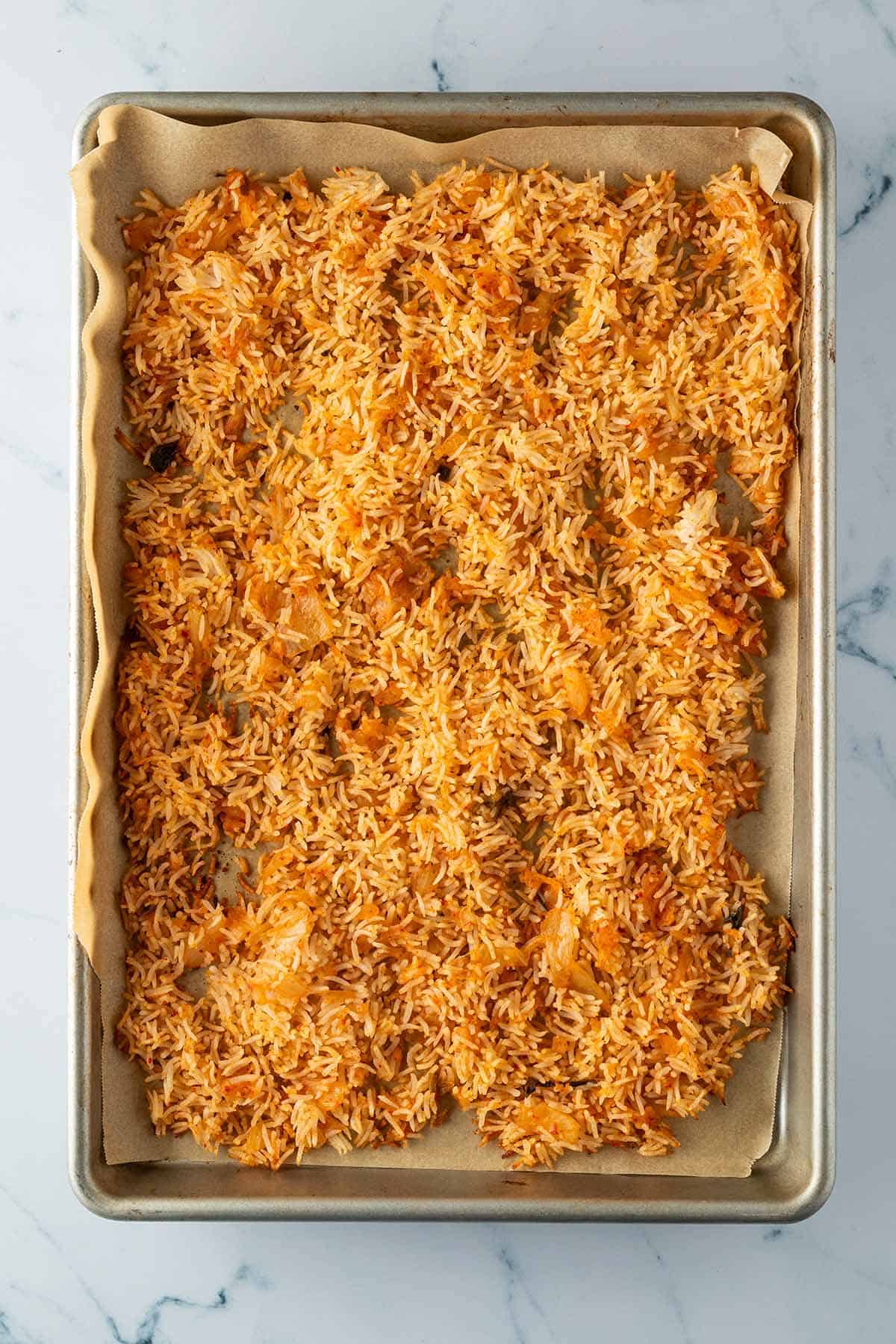 Leicht knuspriger gold-oranger Kimchi Reis auf einem Backblech.