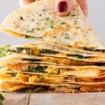 Ein Stapel Quesadillas, von dem einen Hand den ein St&uuml;ck wegnimmt.