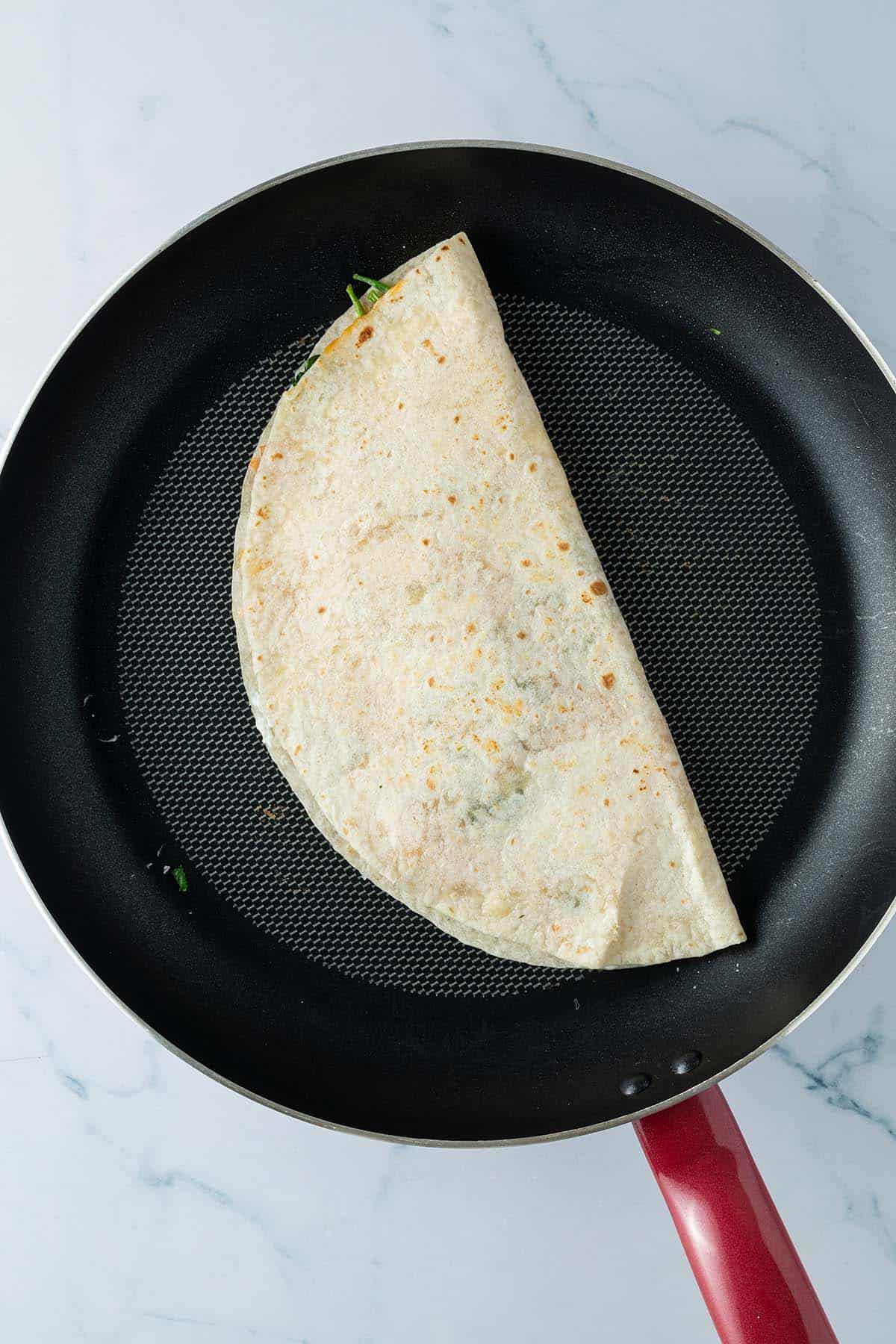 Quesadilla wird in einer Pfanne angebraten.