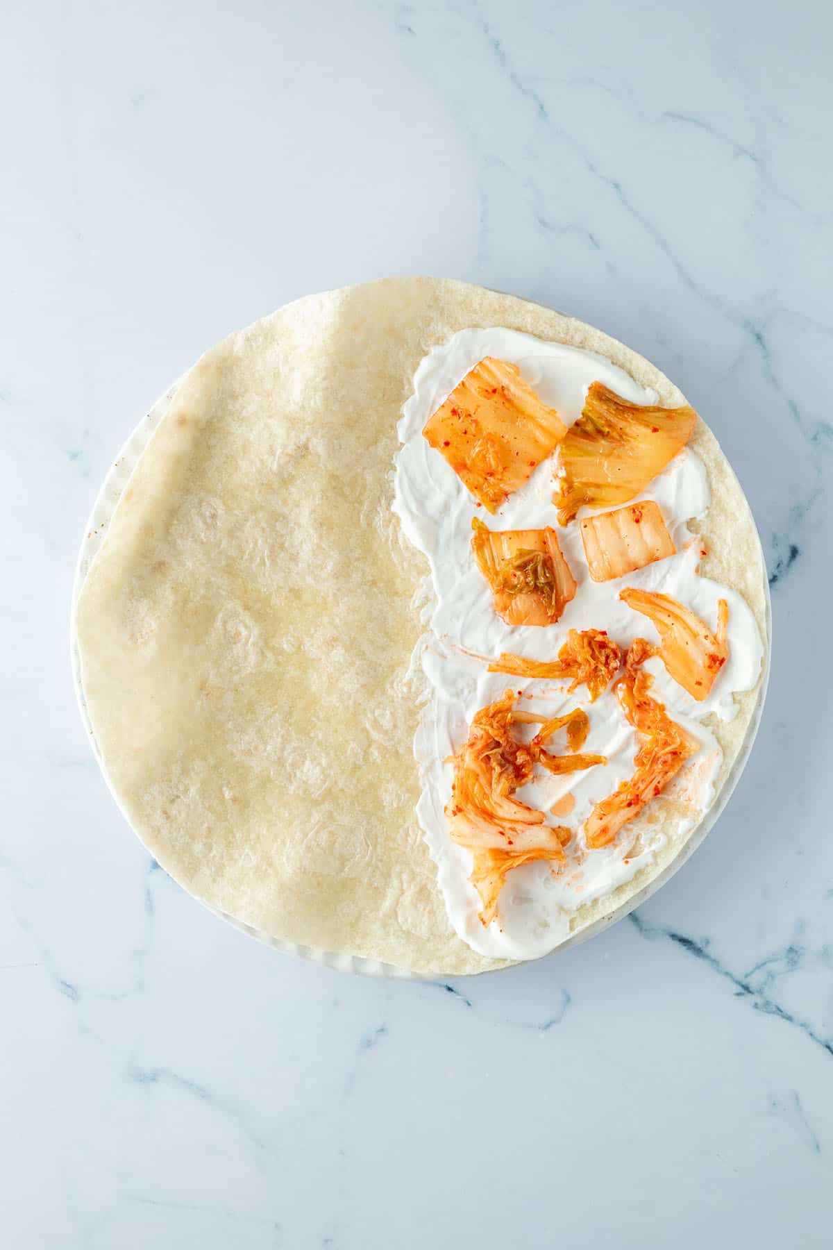 Kimchi und Schmand wurden auf einer H&auml;lfte des Tortillas verteilet.