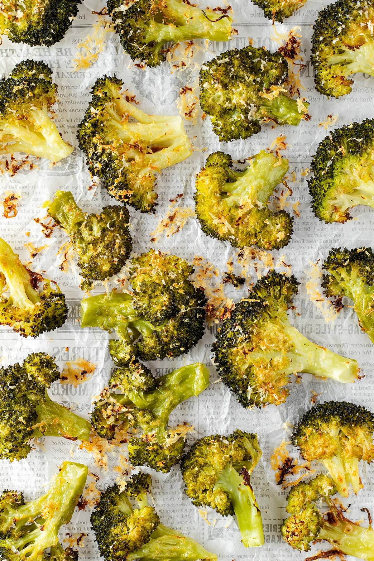 Zerdr&uuml;ckter und mit Parmesan knusprig gebackener Brokkoli auf wei&szlig;em Papier.