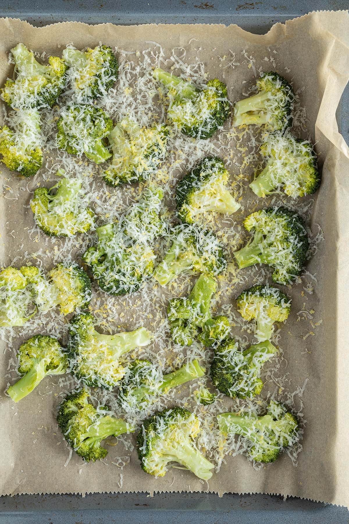 Zerdr&uuml;ckter Brokkoli auf einem Blech mit geriebenem Parmesan und Zitronenschale.