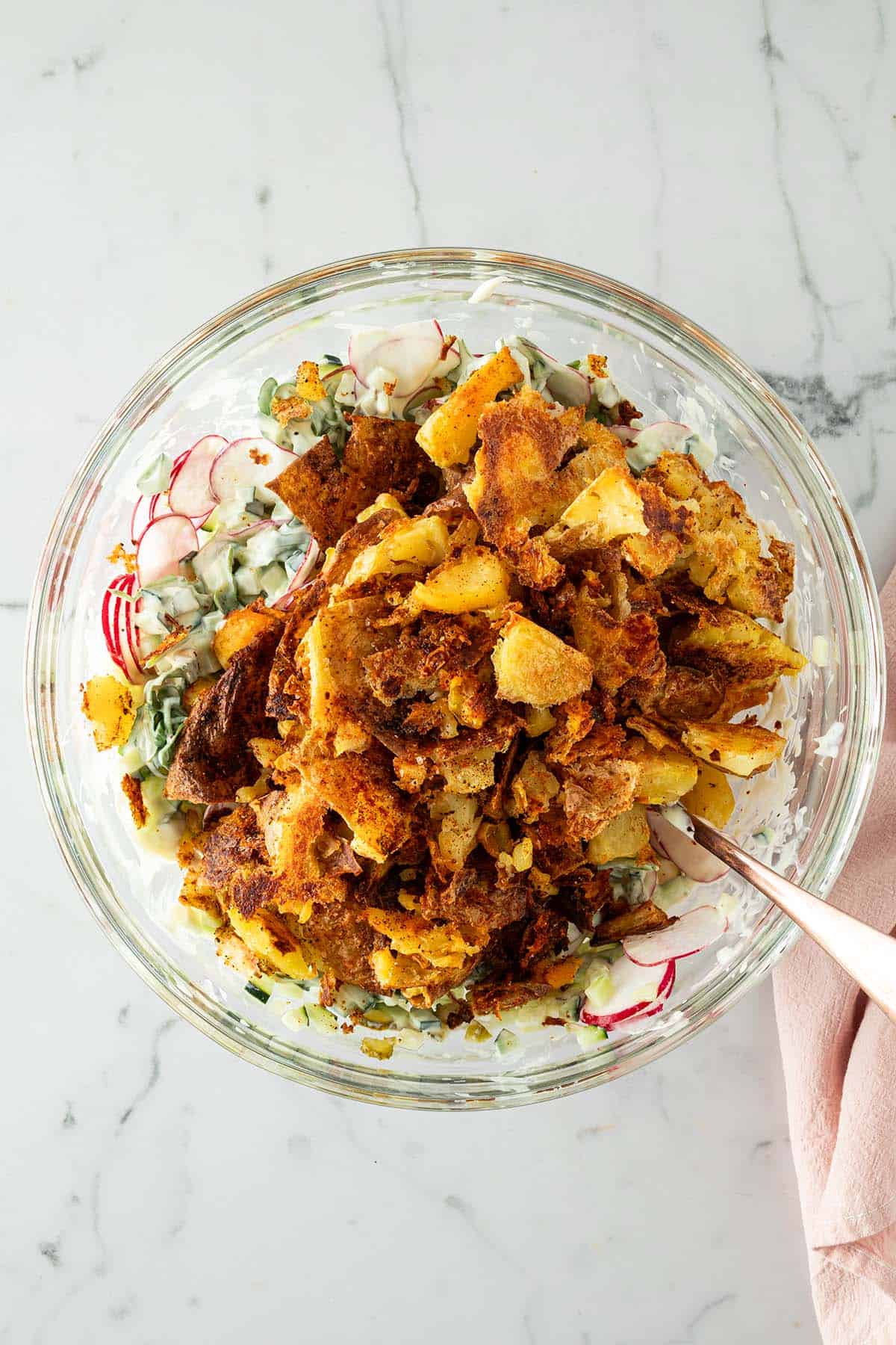 Knusprige Quetschkartoffeln in einer Sch&uuml;ssel mit Gem&uuml;se und einem cremigen Dressing.