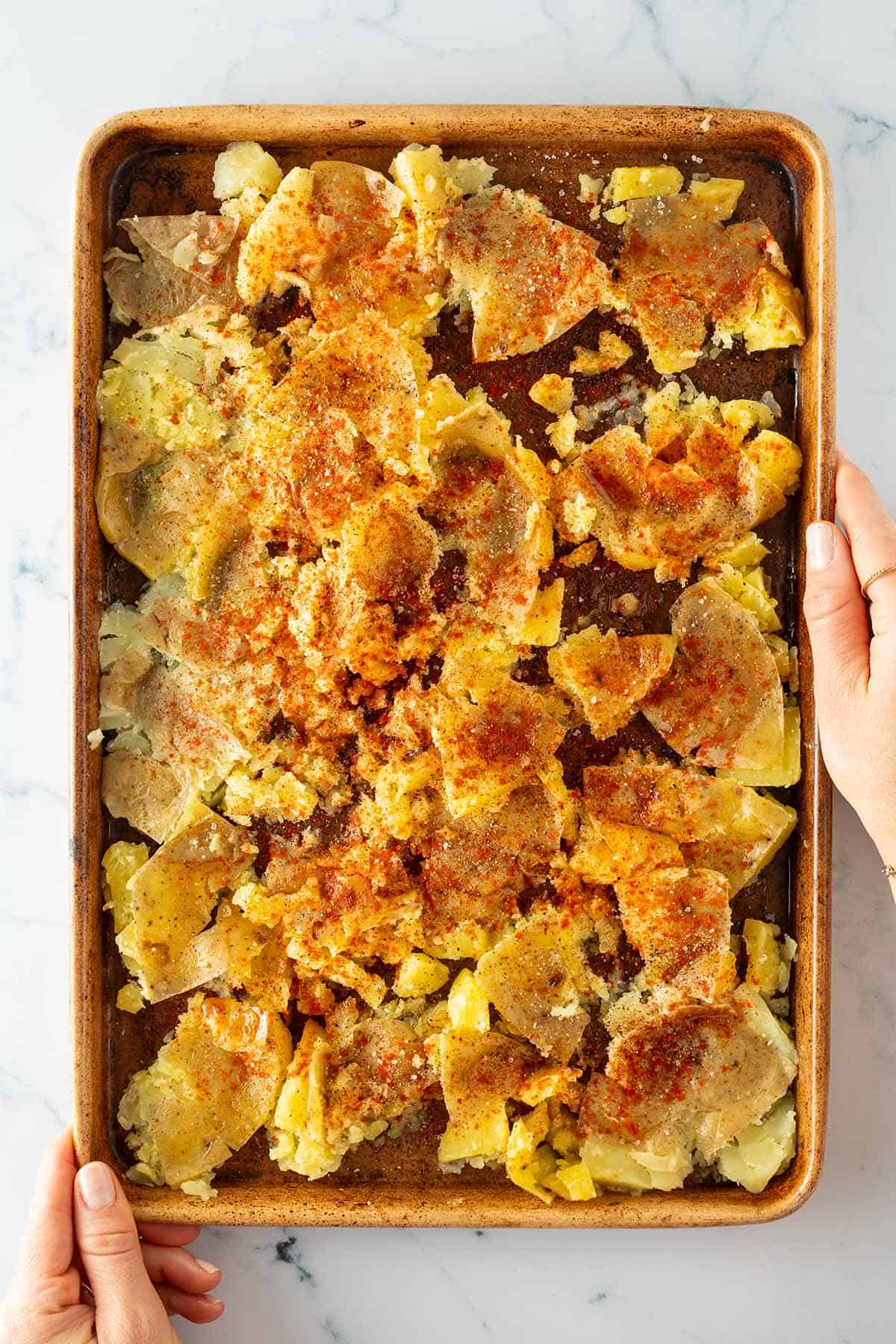 Zerdr&uuml;ckte Kartoffeln auf einem Blech, mit Paprikapulver gew&uuml;rzt.