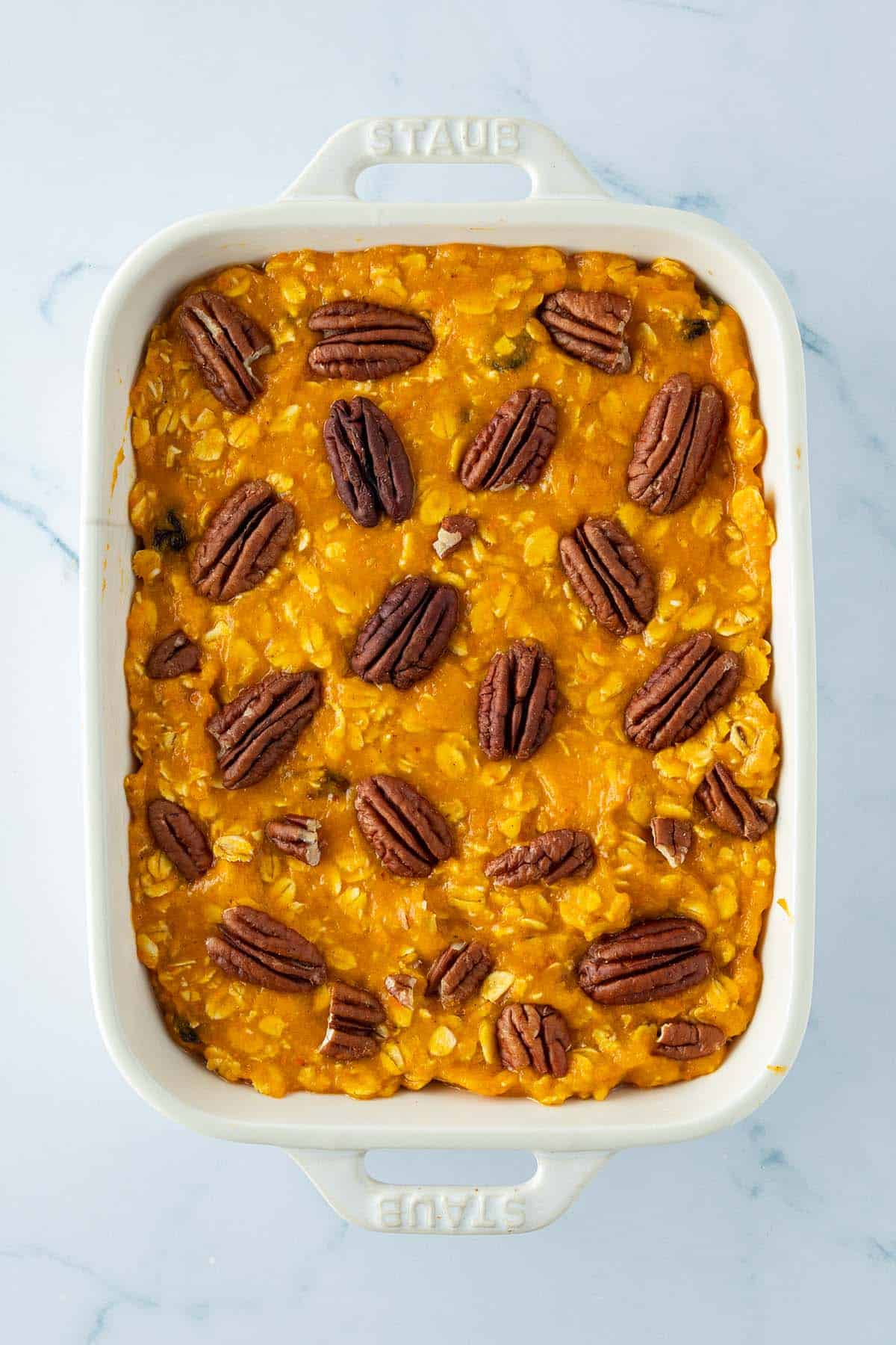Teig f&uuml;r das Baked Oatmeal in einer Auflaufform mit Pecan N&uuml;ssen auf der Oberfl&auml;che vor dem Backen im Ofen.