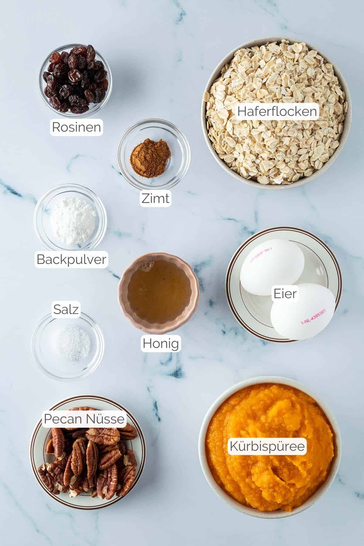 Alle Zutaten mit jeweiligen Textbeschriftungen, die f&uuml;r das K&uuml;rbis Baked Oatmeal ben&ouml;tigt werden.