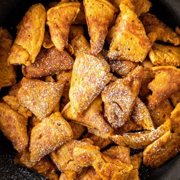 Goldbraune Kaiserschmarrnst&uuml;cke in einer schwarzen Gusseisenpfanne mit etwas Puderzucker.