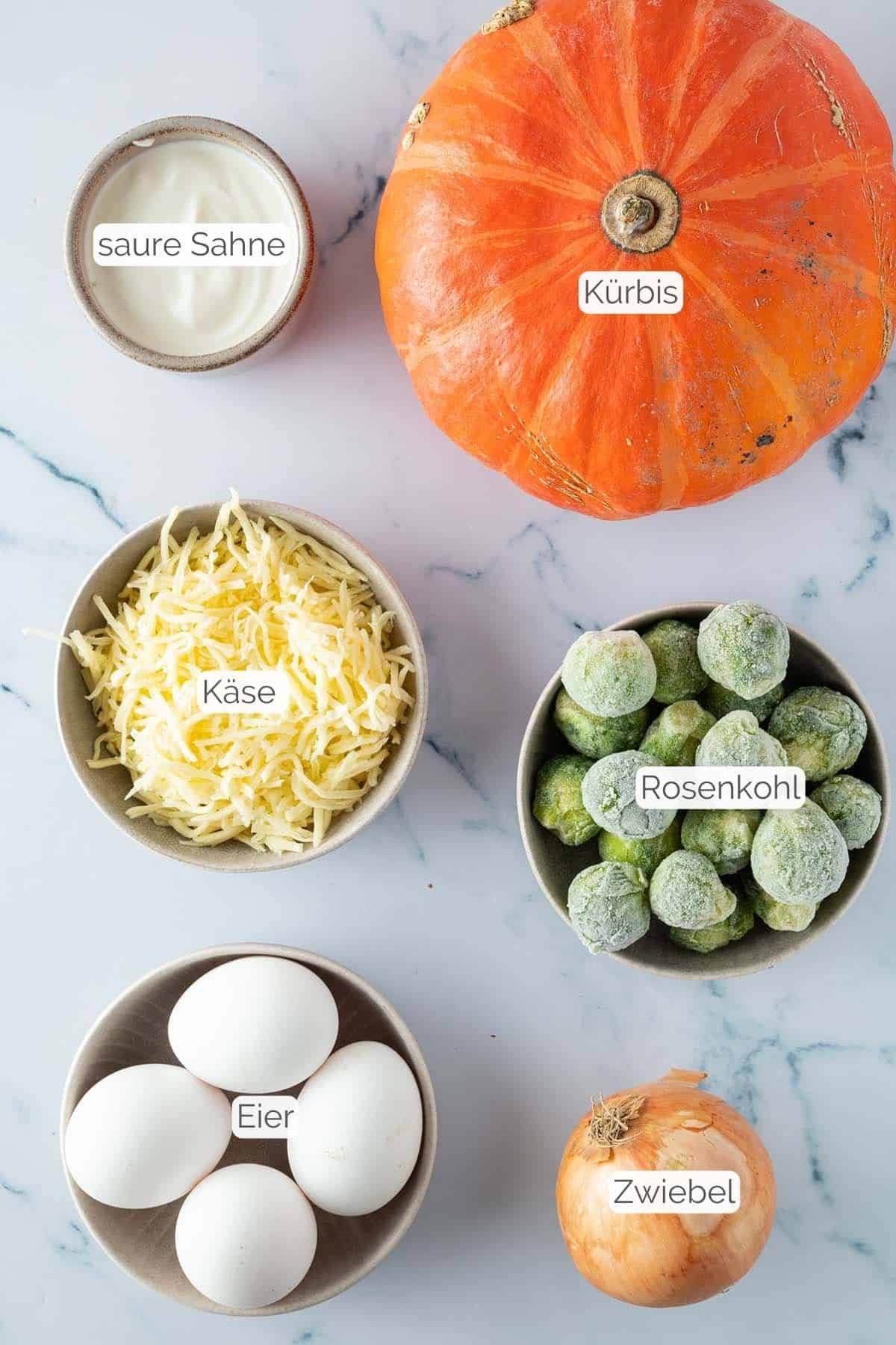 Alle Zutaten mit jeweiligen Textbeschriftungen, die f&uuml;r die K&uuml;rbis Quiche ben&ouml;tigt werden.