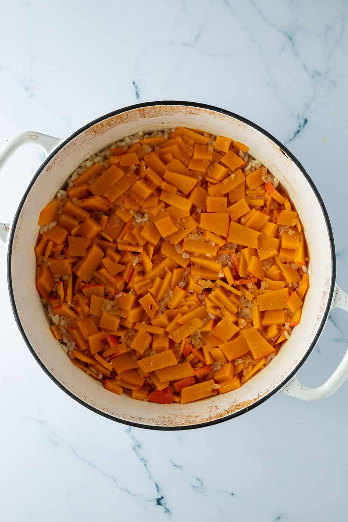 K&uuml;rbis Risotto nach dem Ofen mit den weich gekochten K&uuml;rbisspalten auf der Oberfl&auml;che.