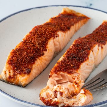 Zwei in der Hei&szlig;luftfritteuse gegarte Lachsfilets auf einem Teller.
