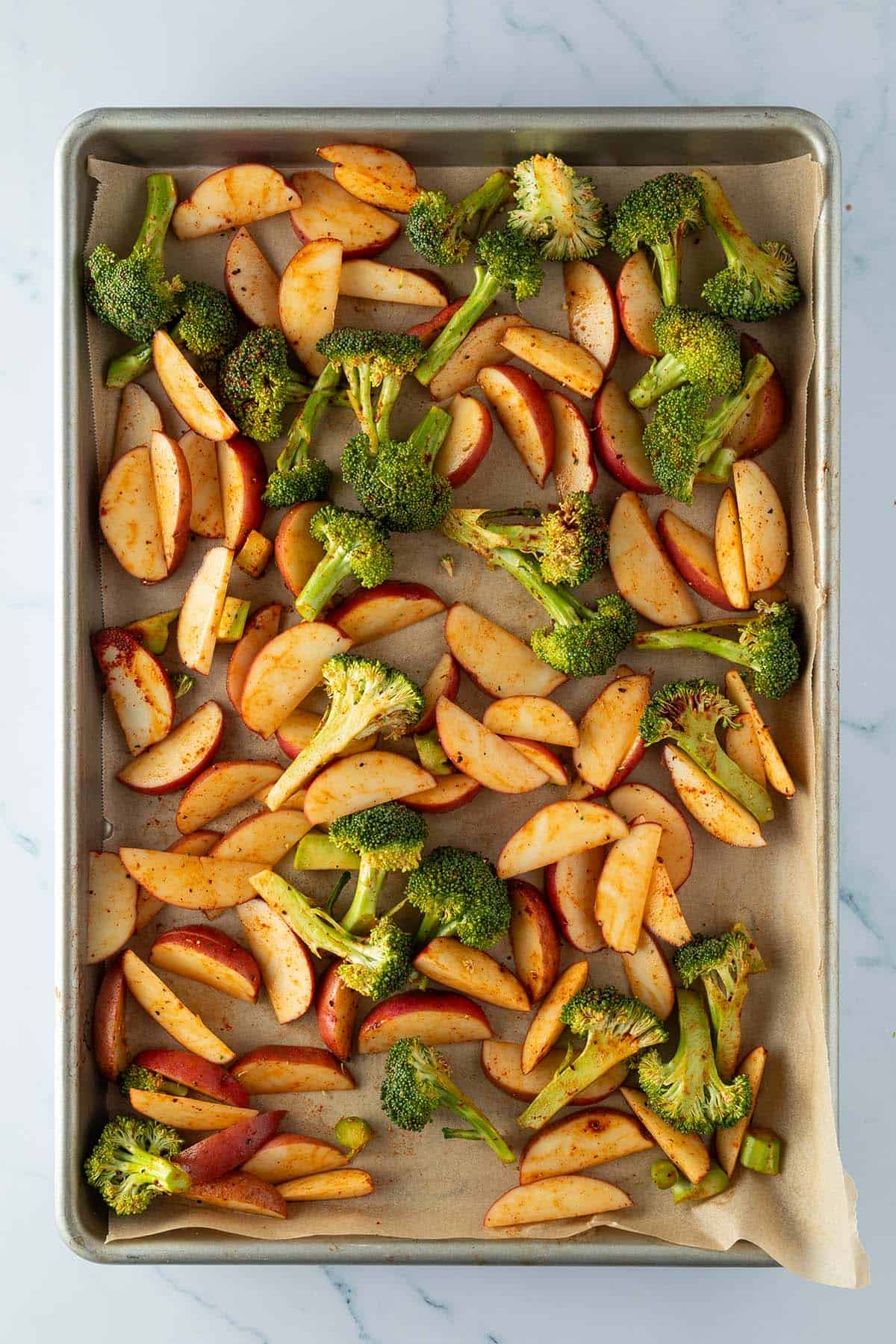 Kartoffelspalten und Brokkoli-R&ouml;schen auf einem Blech.