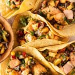 Mehrere Lachs Tacos mit Pfirsich Salsa auf einem St&uuml;ck Backpapier, von oben fotografiert.