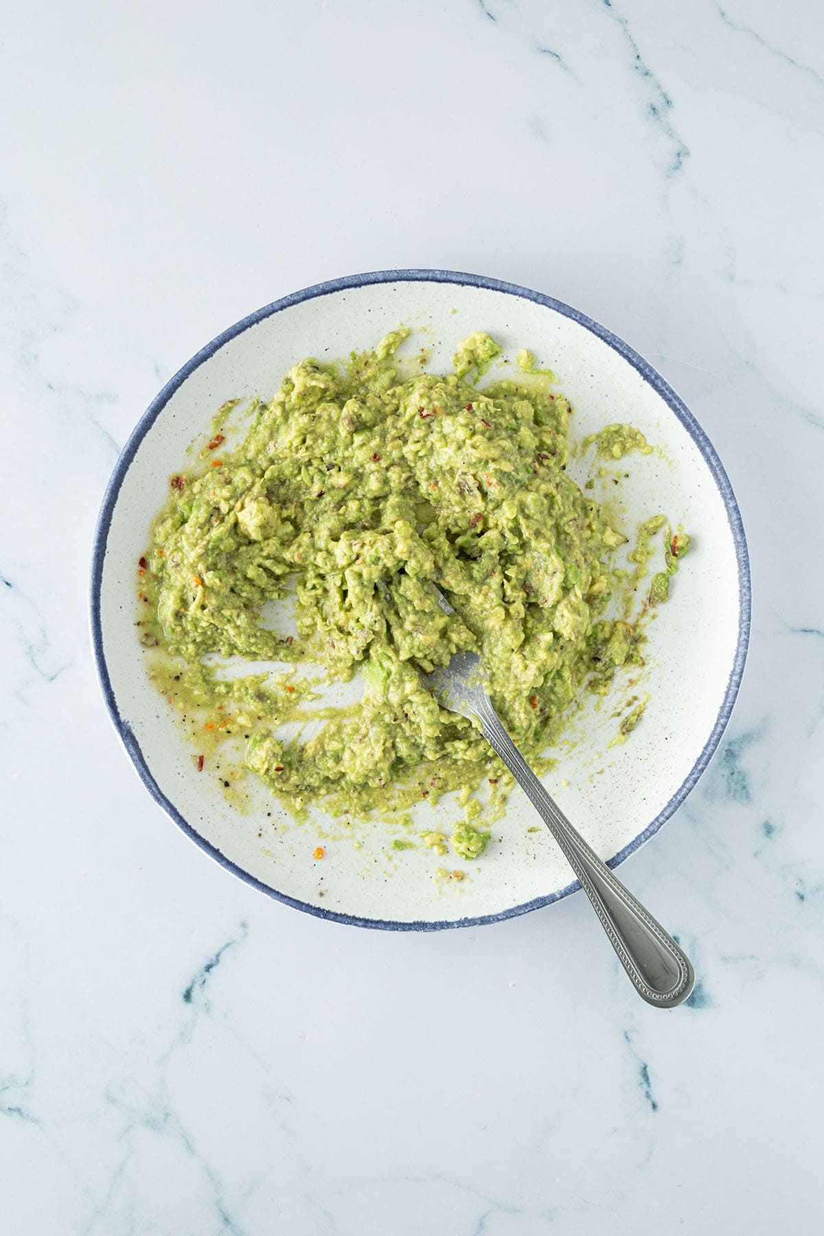 Guacamole wird auf einem Teller mit einer Gabel zubereitet.