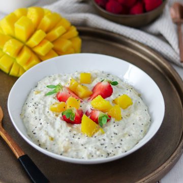 Eine Sch&uuml;ssel Overnight Oats mit Mango und Erdbeeren, Deko im Hintergrund.
