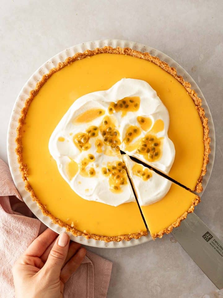Eine Maracuja Tarte wurde angeschnitten und es wird ein Pie-St&uuml;ck herausgehoben.