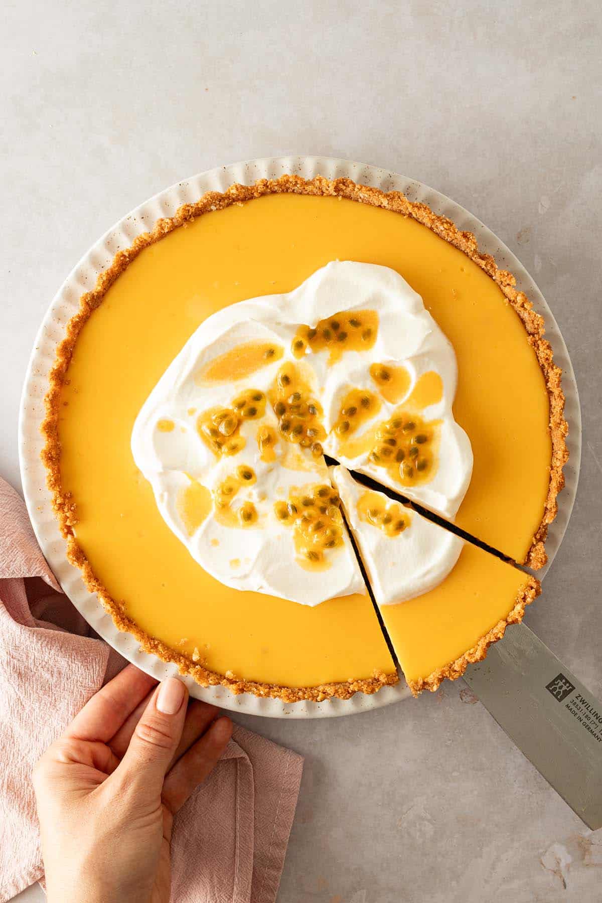 Eine Maracuja Tarte wurde angeschnitten und es wird ein Pie-St&uuml;ck herausgehoben.