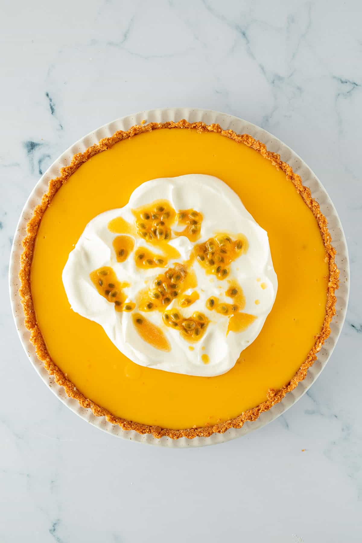 Maracuja Tarte mit frischer Schlagsahne und Passionsfrucht on top auf einem Teller.
