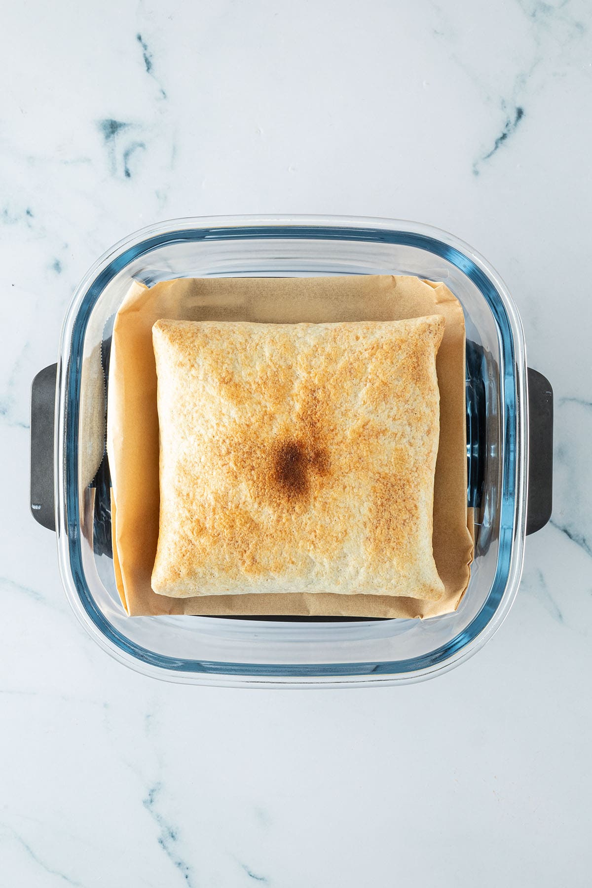 Goldbraun getoastetes Fr&uuml;hst&uuml;ckssandwich in einer Glas-Airfryer mit Backpapier.