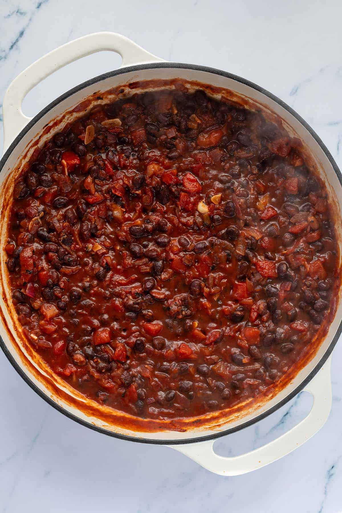 Schwarze Bohnenpfanne in einer eingedickten Tomatensauce nach 20 Minuten auf dem Herd.