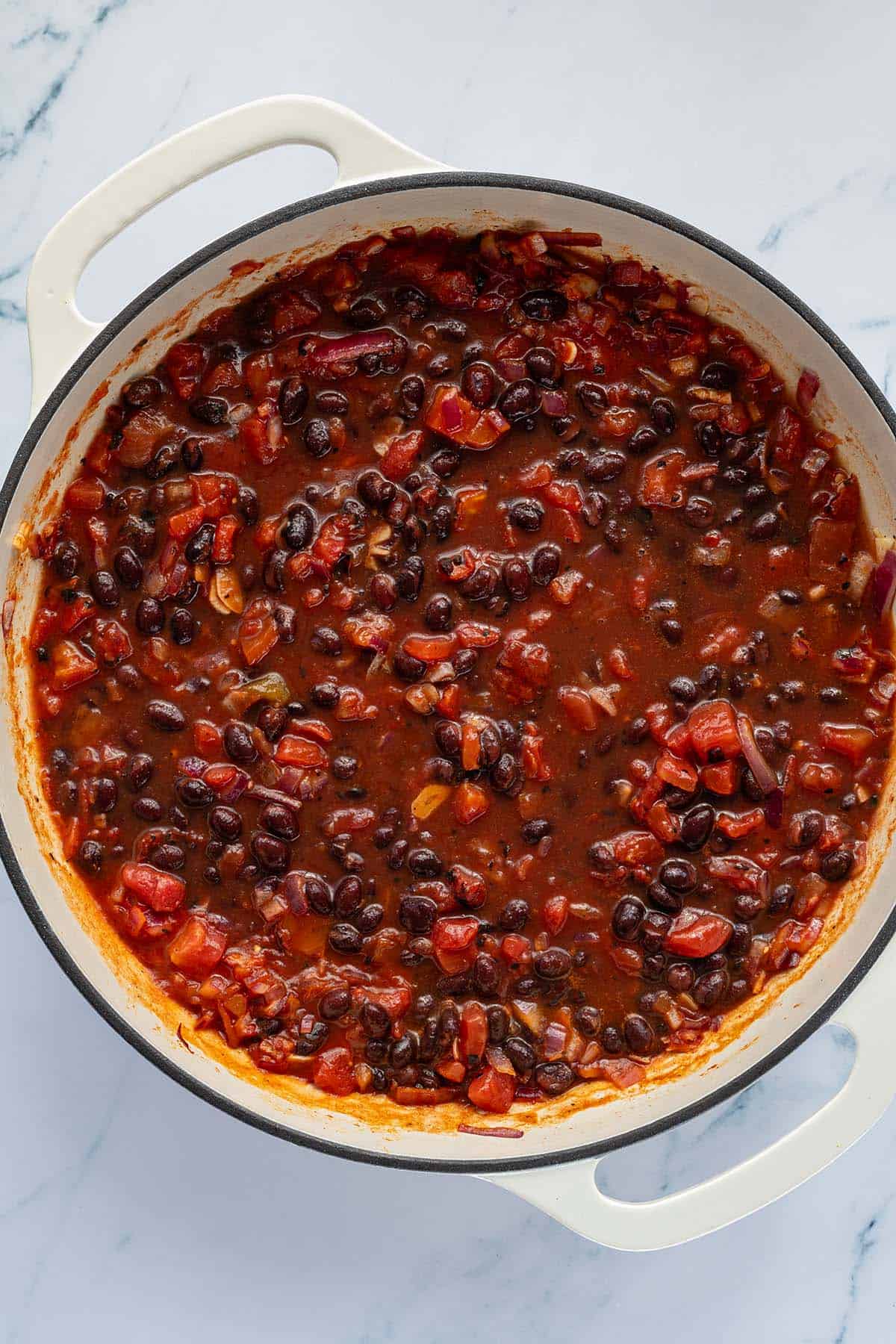 Schwarze Bohnen in einer st&uuml;ckigen Tomatensauce vor dem Kochen.