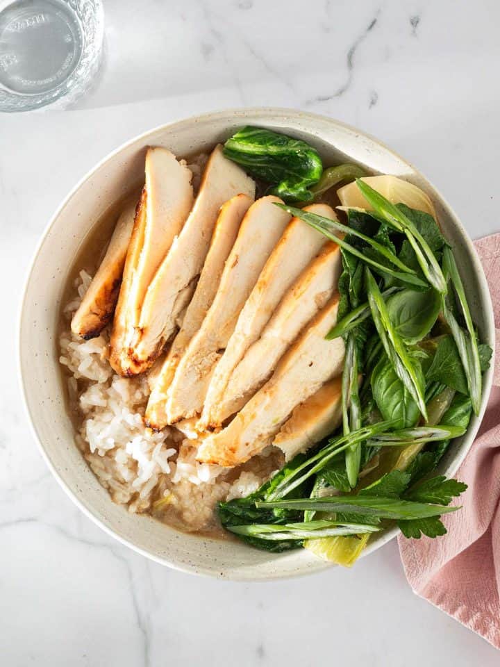 Miso Broth Bowl mit Reis, H&auml;hnchen und Pak Choi in einer hellen Sch&uuml;ssel, serviert mit Fr&uuml;hlingszwiebeln und Kr&auml;utern.